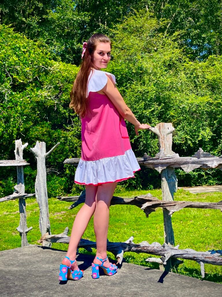 a girl wearing colorful dresses in pink colors, pink ribbon on her hair and blue high heels sandals