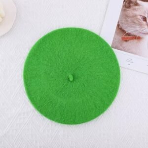 bright green beret lying on the white table, a white candle and a picture of cat lying next to it