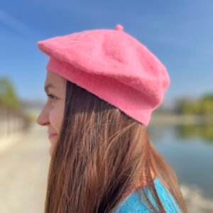 woman turned to her side wearing candy pink beret, the blue sky in the background