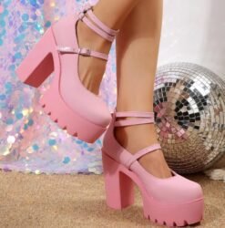 woman wearing chunky pink heels and lifting one leg, disco ball behind her