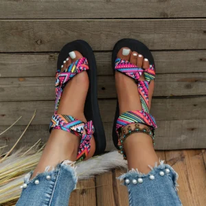 woman wearing colorful flat sandals, wooden floor under them