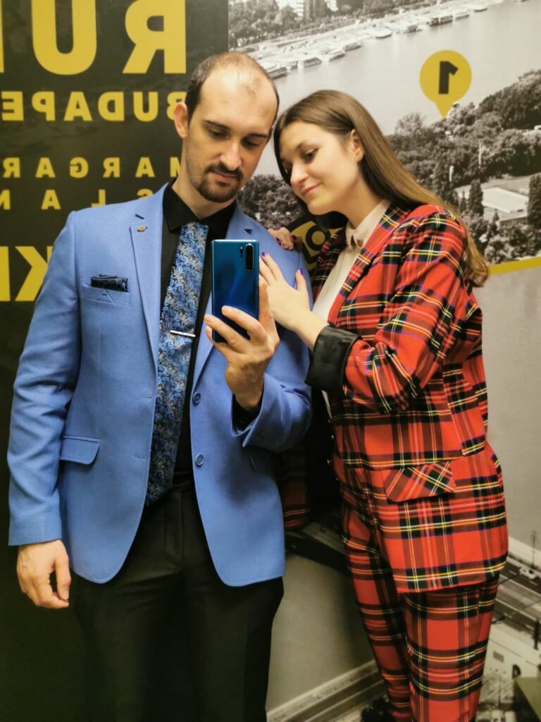 a couple wearing colorful suits - a man wearing blue suit with black pants and a woman red with black checks.