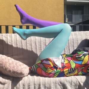 colorful tights blue and purple side view on a model's legs, she is sitting on a pale pink couch