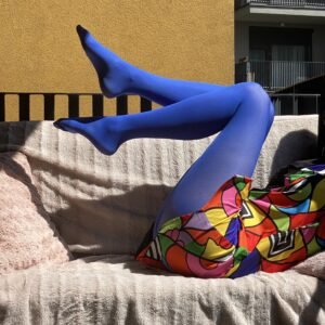 dark blue tights side view on the legs of a model, she is sitting on a pale pink sofa, only her legs are visible