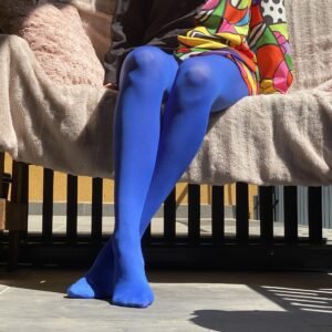 dark blue tights front view on the legs of a model, she has crossed legs and is sitting on a pale pink sofa