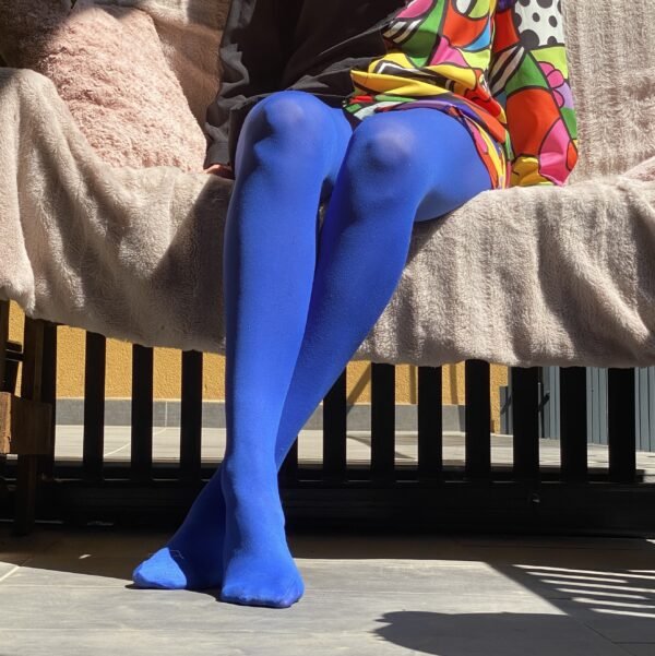 dark blue tights front view on the legs of a model, she has crossed legs and is sitting on a pale pink sofa