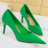 green pointed toe heels standing on a white carpet