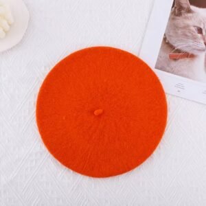 orange beret lying on the white table, a white candle next to it