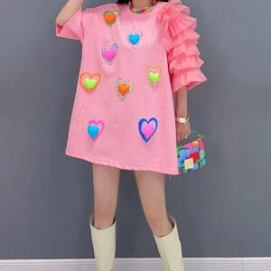 woman wearing pink dress with hearts and white boots, grey wall in the background