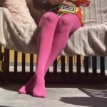 pink tights front view on the legs of a model, pale pink couch in the background