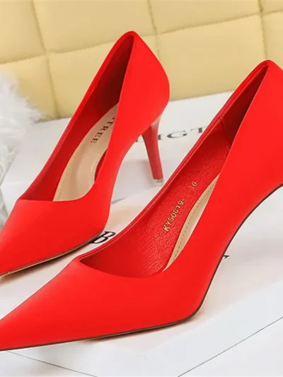 red pointed toe heels standing on a white carpet