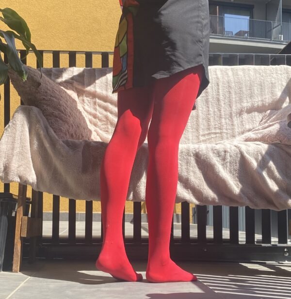 red tights back view on a model, a couch with pale pink bedsheets in the background