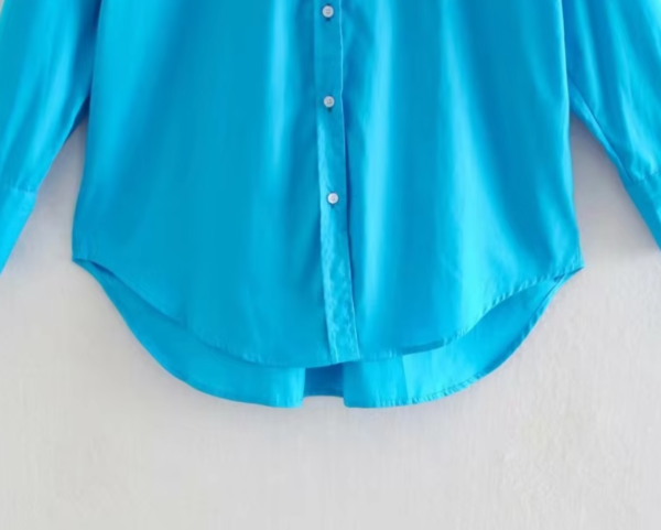 turquoise blouse front view on a hanger, bottom part visible