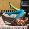 woman lying on a pink sofa wearing two colors colorful tights, blue and green variation