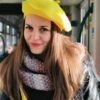 yellow beret front view on a model, a model is smiling and wearing a grey scarf