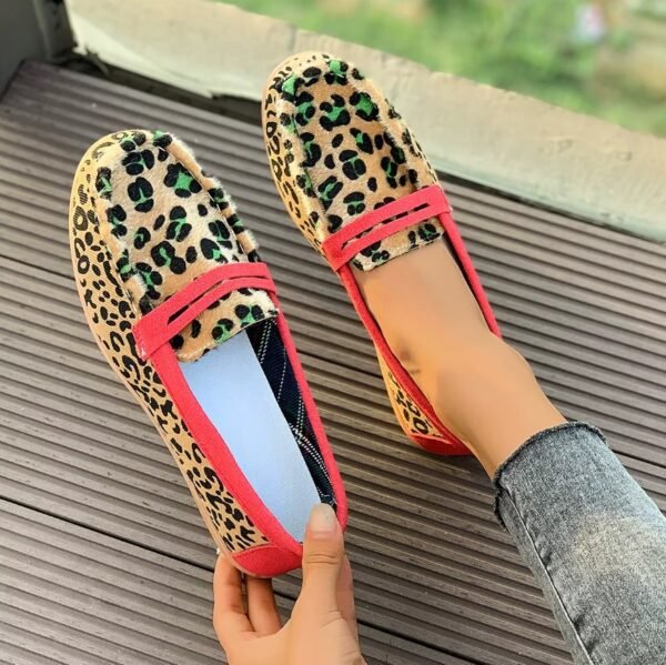 woman wearing one leopard print loafer and holding the other on the the brown floor