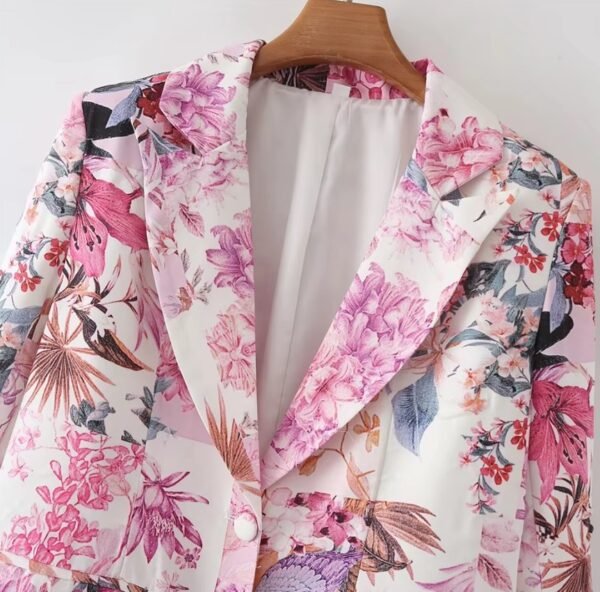 the upper part and the collar of the pink floral blazer on a hanger