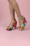 woman wears multicolor wedges on pink surface