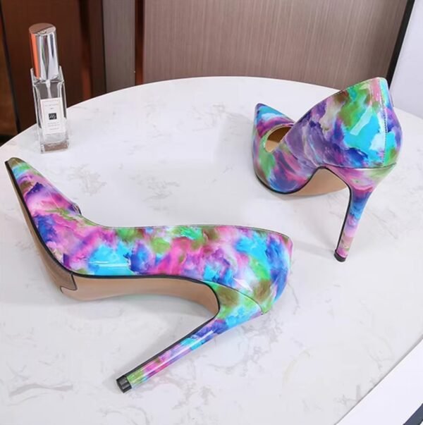 artistic colorful heels standing on the white table, a bottle of perfume next to them