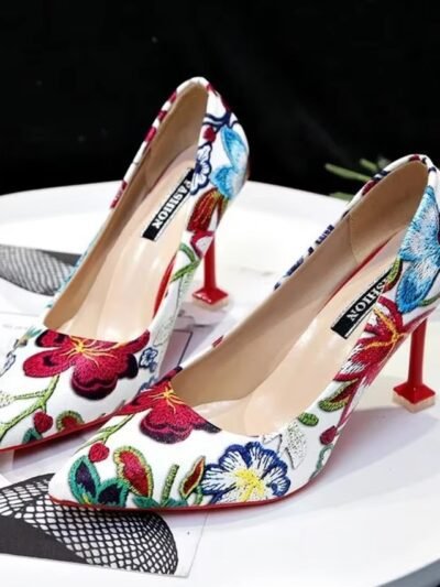 colorful floral heels standing on the white table, black wall in the background