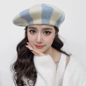 woman with dark brown hair wearing blue colorful striped beret and a white sweater