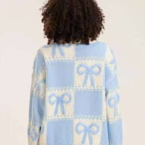 woman with curly brown hair turned to her back wearing blue colorful sweater with ribbons