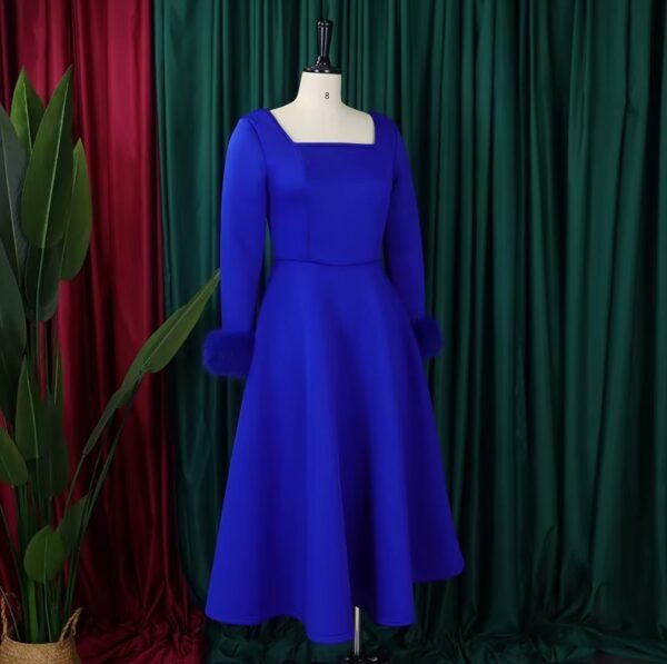 side view of blue long-sleeved colorful dress, green and red curtains in the background