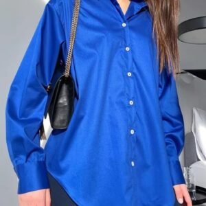 woman wearing blue oversized colorful blouse, navy pants and a black purse