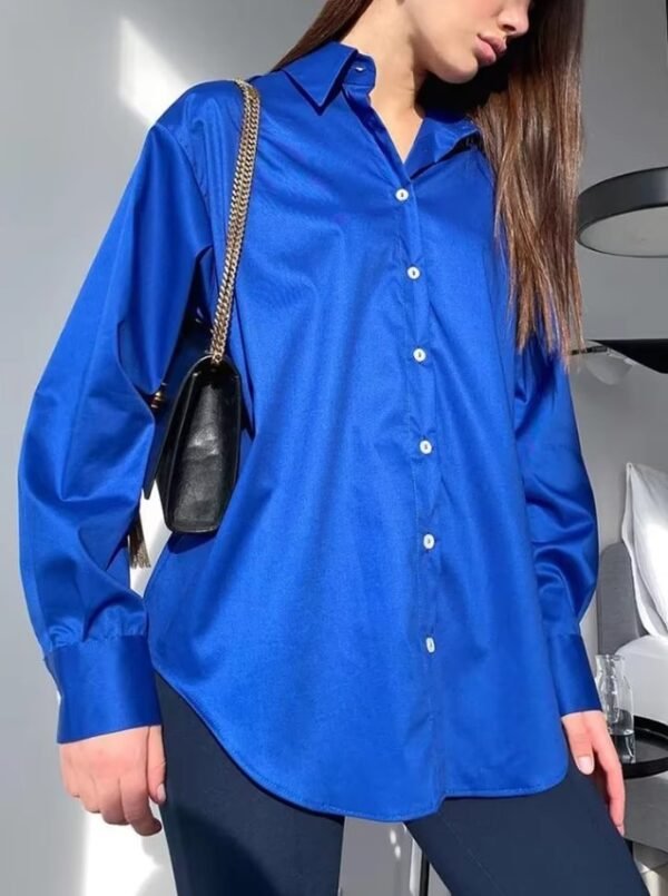 woman wearing blue oversized colorful blouse, navy pants and a black purse