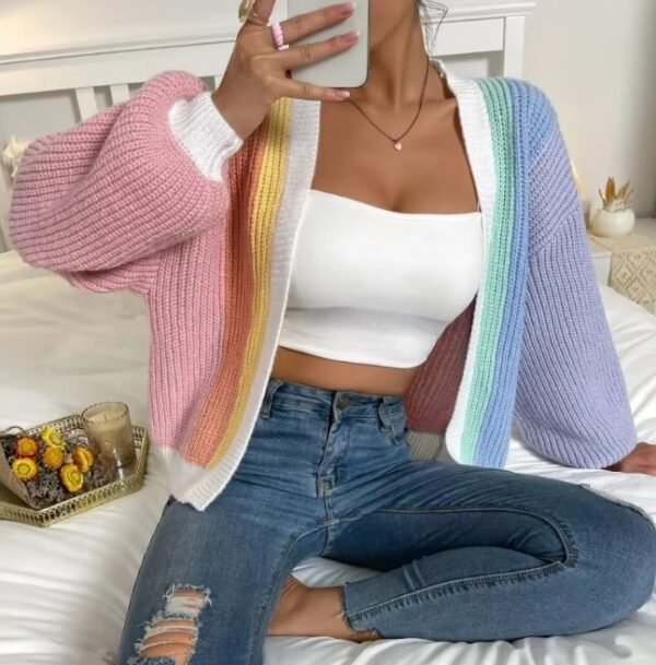 woman wearing casual colorful cardigan, white top and jeans, she is sitting on a bed