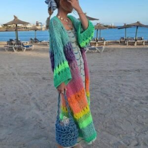 woman turned to her side wearing colorful Bohemian cardigan and grey loafers on the beach