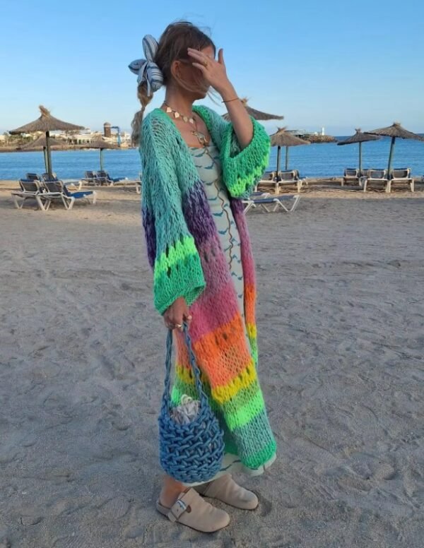 woman turned to her side wearing colorful Bohemian cardigan and grey loafers on the beach