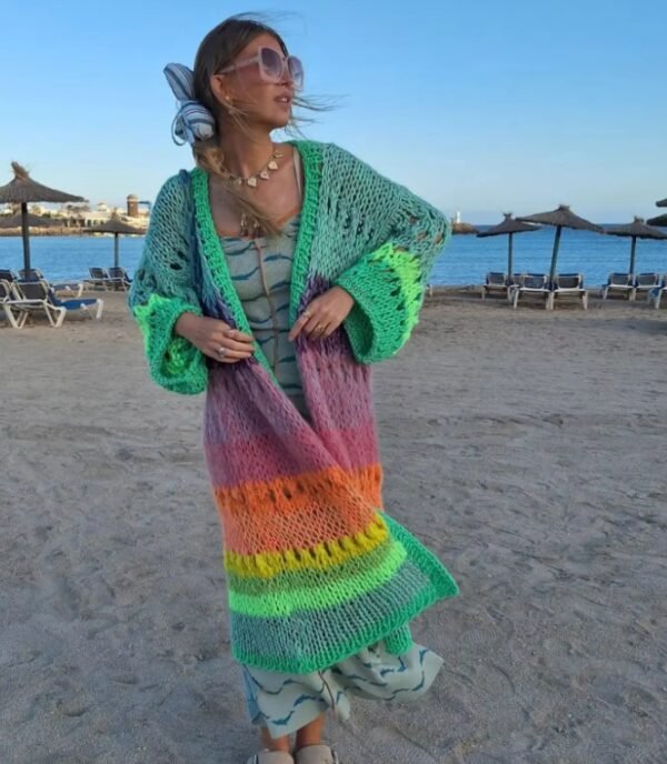 woman wearing colorful Bohemian cardigan and a green dress, she has a blue ribbon in her hair, beach in the background