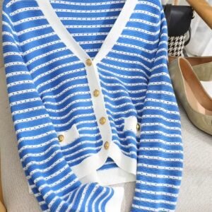 colorful blue cardigan lying on the white sofa, grey heels behind it