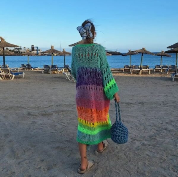 woman turned to her back wearing colorful Bohemian cardigan and carrying a blue bag on the beach