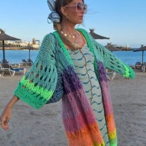 woman wearing colorful Bohemian cardigan and a green dress, beach in the background