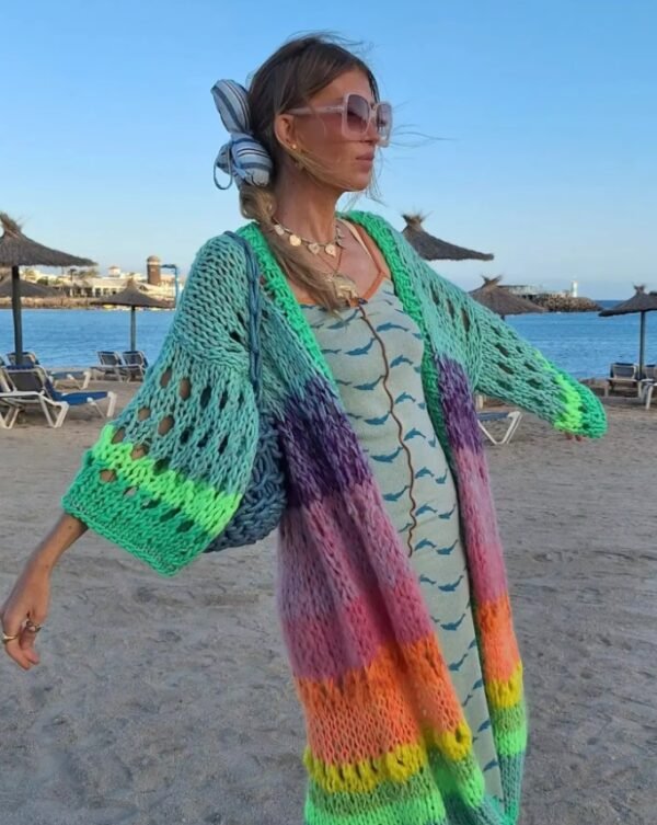 woman wearing colorful Bohemian cardigan and a green dress, beach in the background