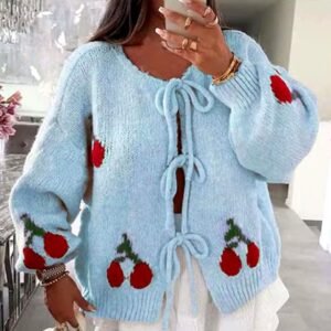 woman with brown hair wearing colorful cherry cardigan and w white skirt