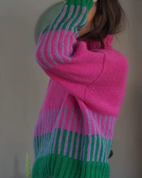 woman wearing colorful color blocking sweater and lifting one hand