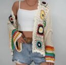 woman wearing colorful crochet cardigan, white top and jeans shorts on the white background
