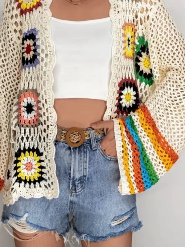 woman wearing colorful crochet cardigan, white top and shorts - she is having one hand in the pocket