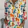 woman wearing colorful dogs blouse, white wall behind her