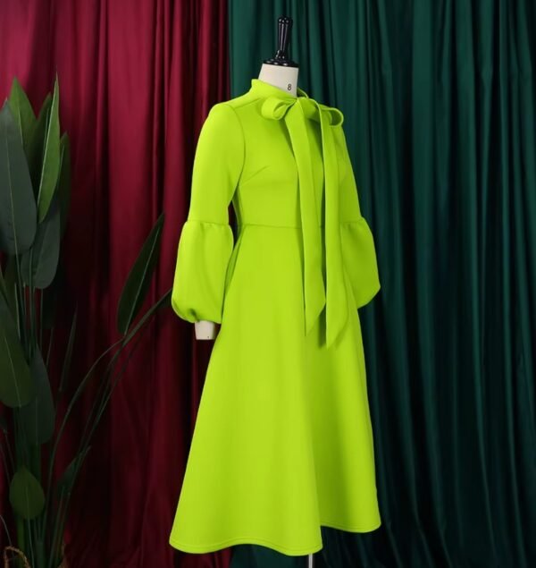 side view of green colorful dress with a bow, green and red curtains in the background