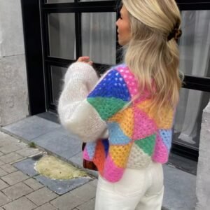 blonde woman turned to her back wearing colorful patchwork cardigan and white jeans