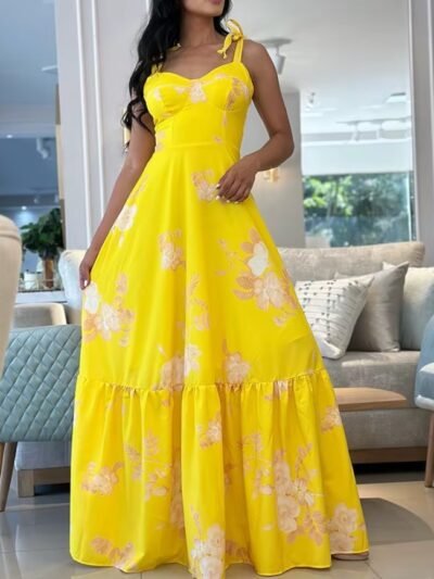 woman wearing colorful sleeveless dress, grey sofa with pale blue pillows behind her