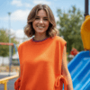 woman with short blonde hair wearing orange colorful sleeveless sweater on the playground