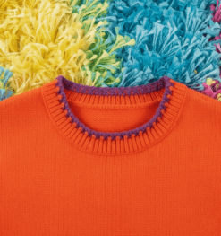 collar of orange variation of colorful sleeveless sweater on a colorful carpet