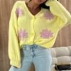 woman wearing colorful spring cardigan and jeans, wooden wall behind her