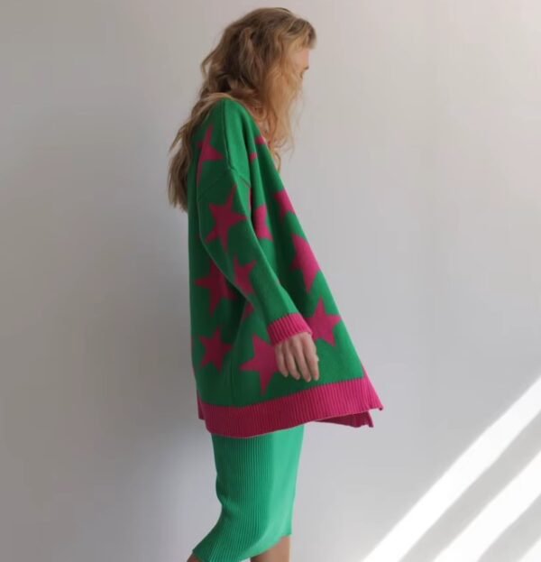 woman turned to her side wearing colorful stars cardigan and green skirt, white wall in the background