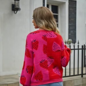 woman turned to her back wearing colorful strawberry cardigan, white house in the backgorund